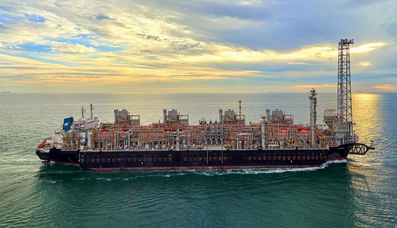 FLNG Hilli underway, painted bow, flare tower forward.