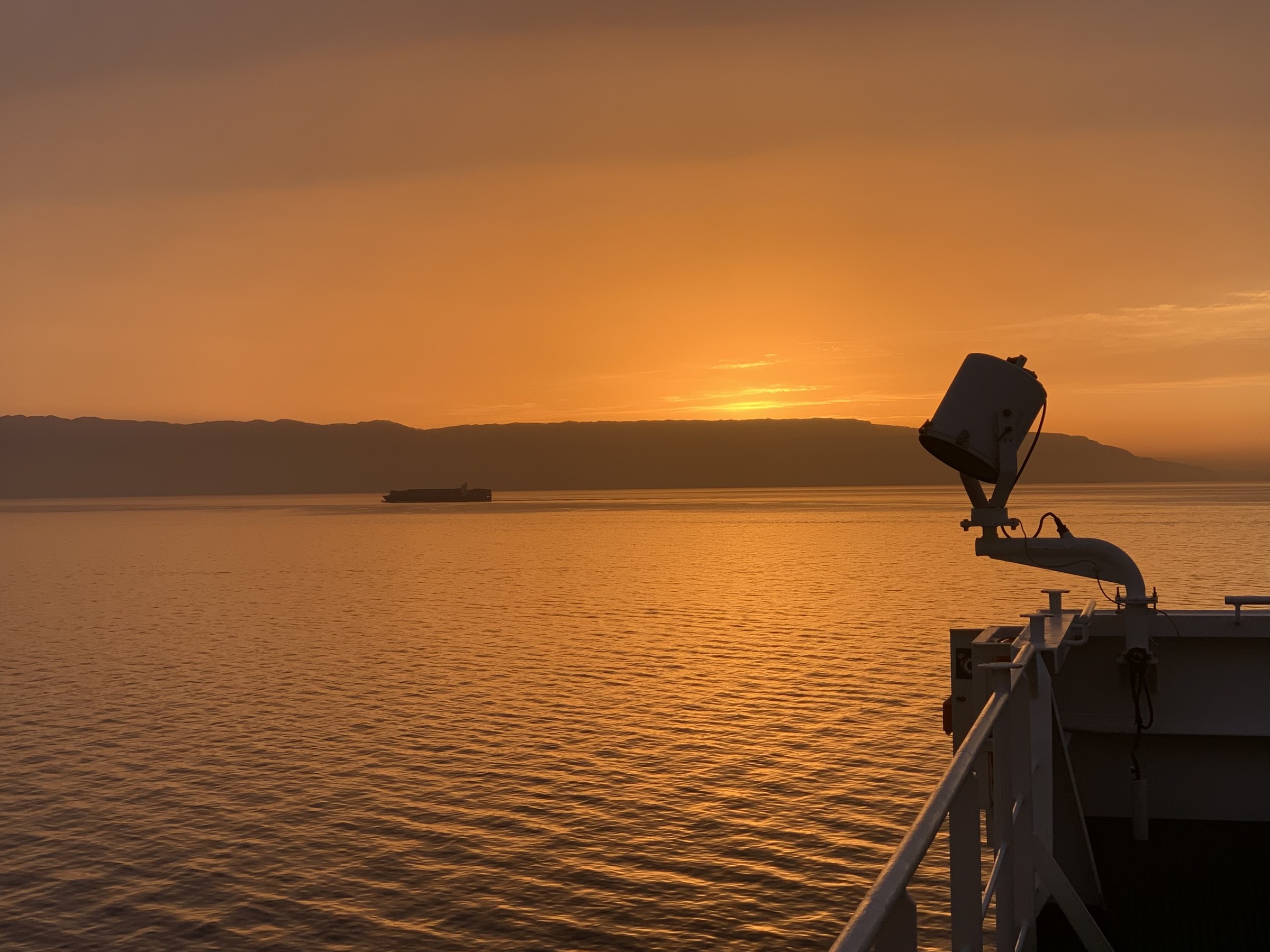 Sunset from the bridge wing; distant hull on the beam. Gulf of Suez.